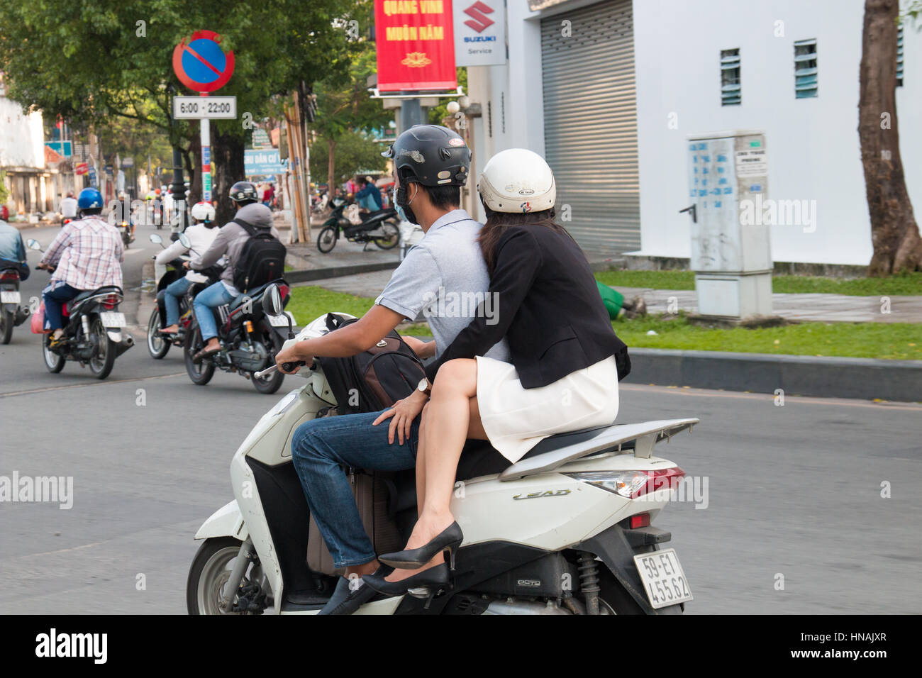 Novio y novia montando su scooter por las calles de la ciudad de Ho Chi Minh, Vietnam Foto de stock