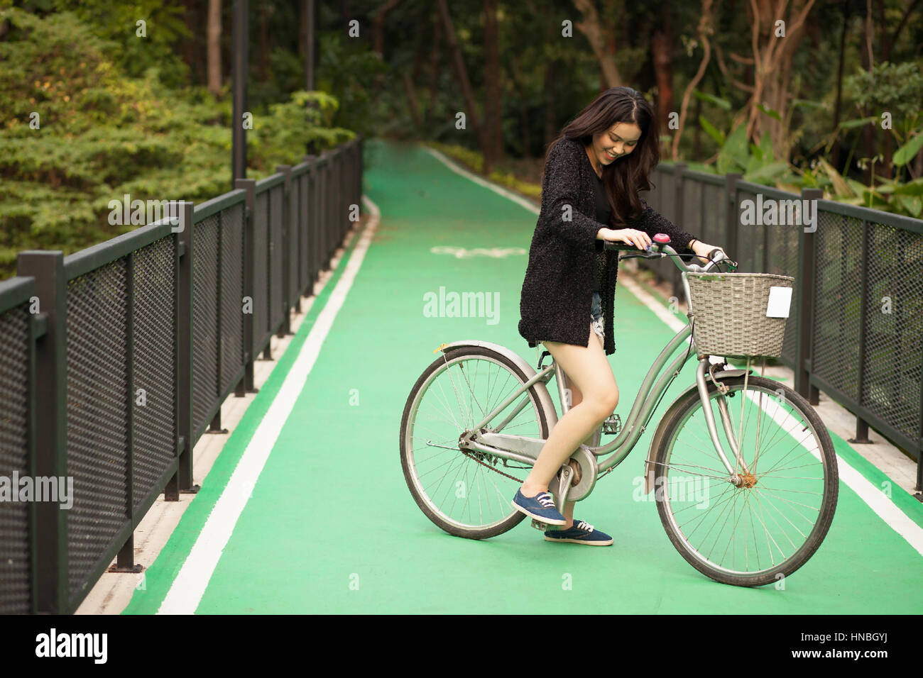 Bonita muchacha tailandesa montando bicicleta en el parque Foto de stock
