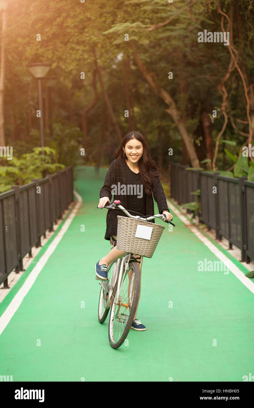 Bonita muchacha tailandesa líder en bicicleta en el parque Foto de stock
