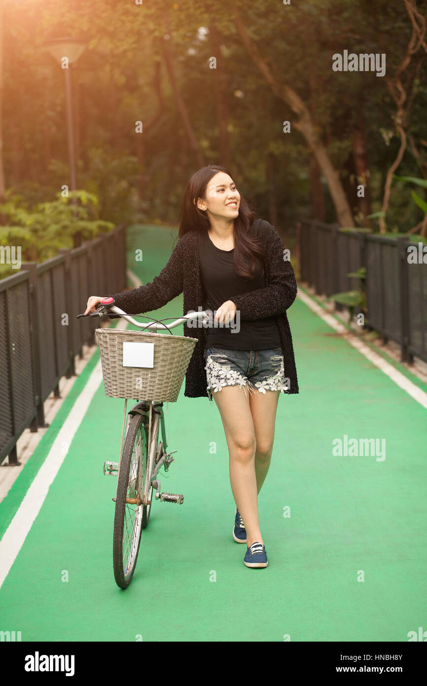 Bonita muchacha tailandesa líder en bicicleta en el parque Foto de stock