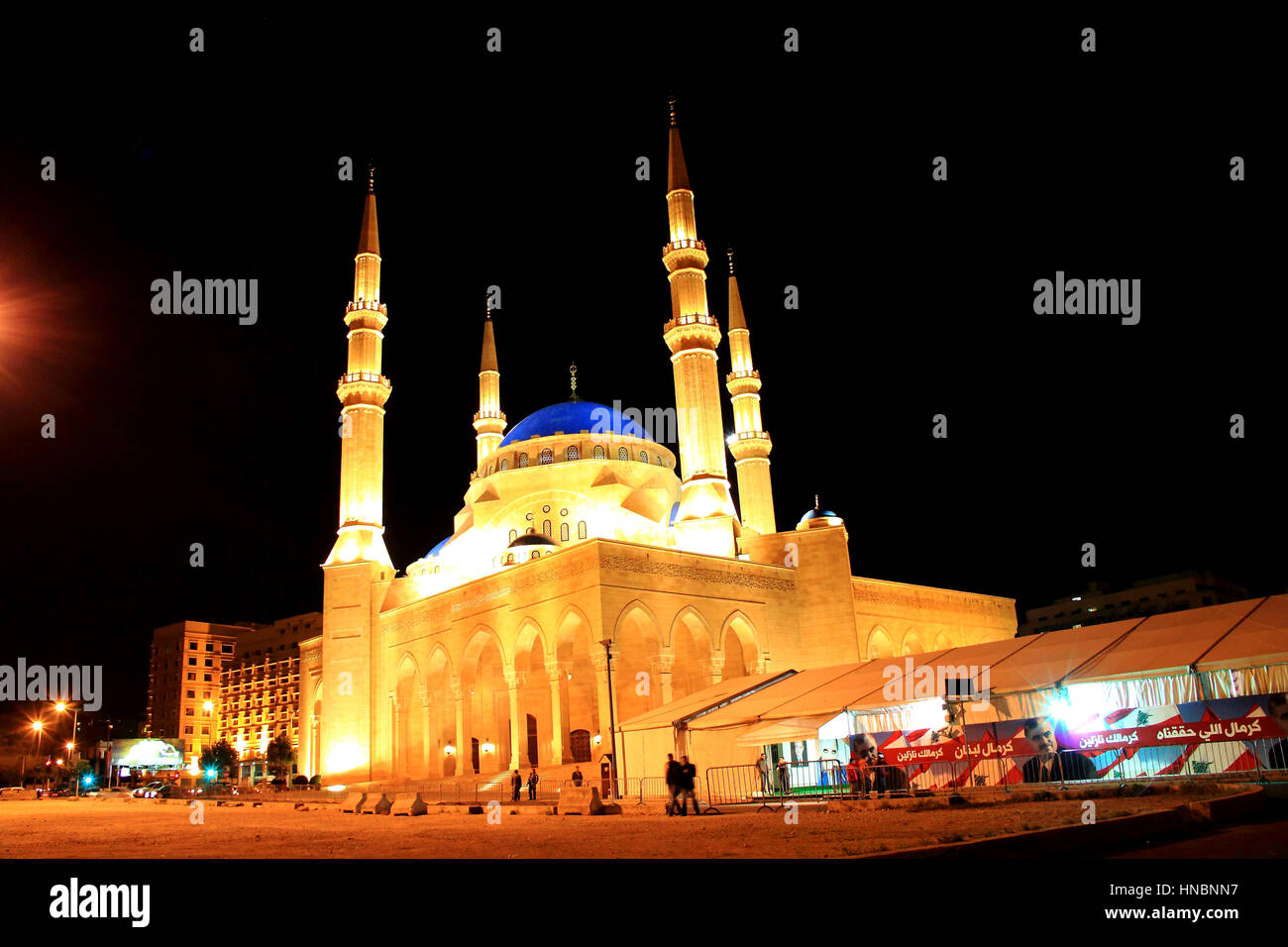La mezquita de Al Amin iluminadas por la noche en Beirut, Líbano, carpas con los anuncios políticos e imágenes de Hariri y la bandera libanesa junto a Foto de stock