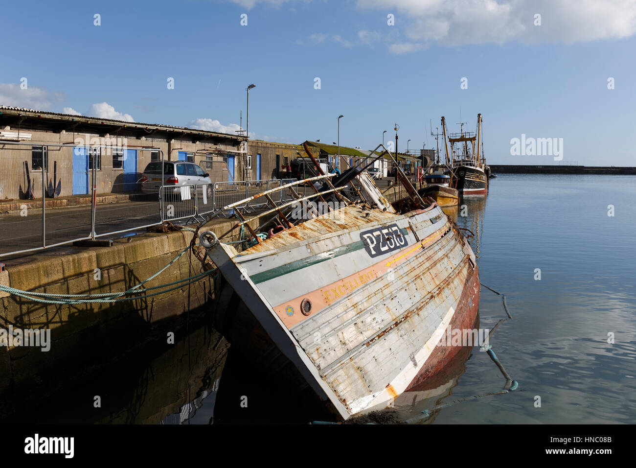 Una línea de barcos de pesca y la retirada abandonados yacen junto al East Quay muralla en Newlyn Harbour Foto de stock