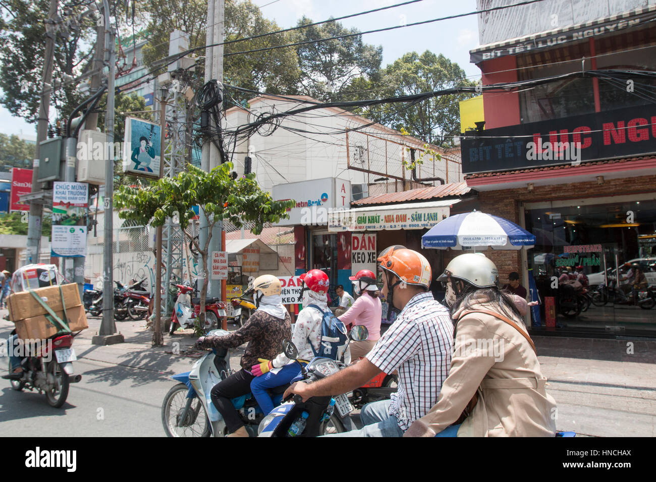 Scooter motoristas que viajan a través de la ciudad de Ho Chi Minh en Vietnam Asia Foto de stock