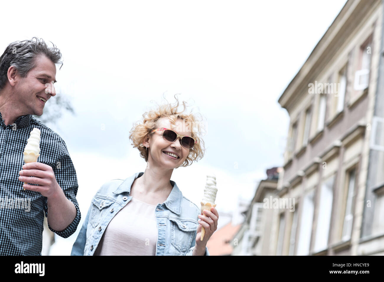 Pareja de mediana edad sonriente Celebración conos de helado en día soleado Foto de stock