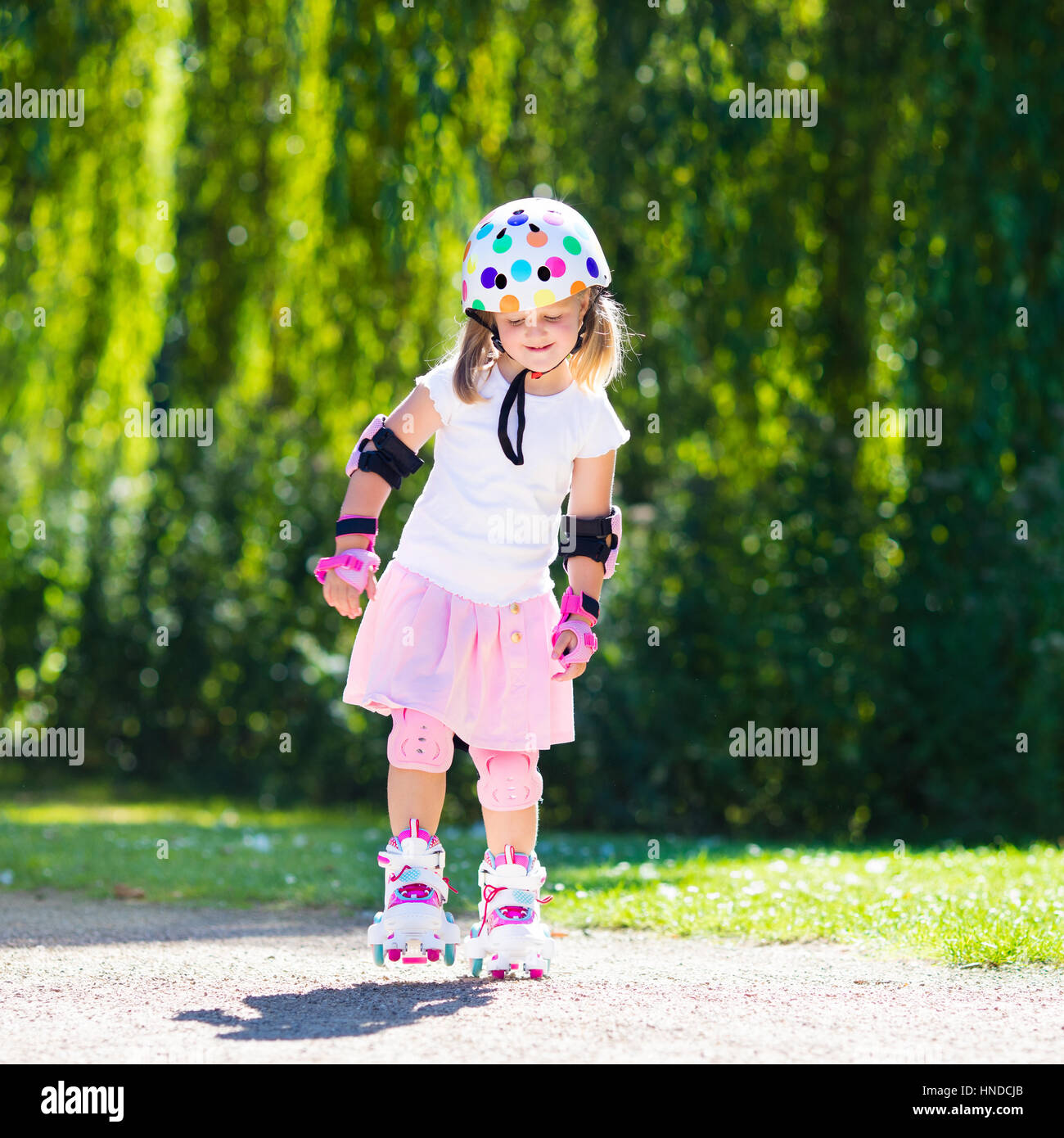 Niña aprendiendo a patines en el parque soleado de verano. Un niño llevaba  protección - rodilleras y coderas, muñequeras y casco de seguridad seguro  de Lod Fotografía de stock - Alamy