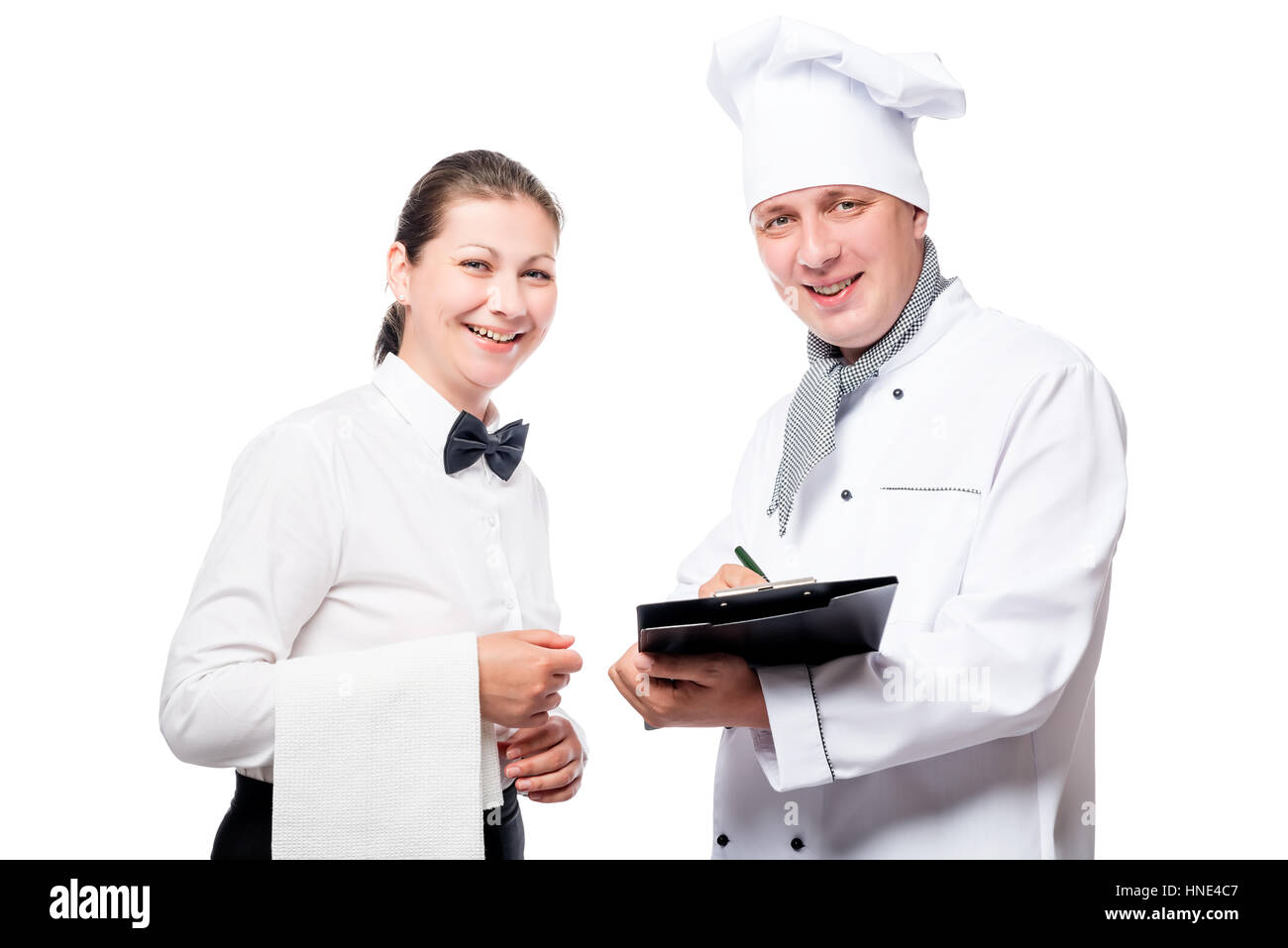 Chef con una carpeta y un camarero con una toalla sonriente sobre un fondo blanco en el studio Foto de stock