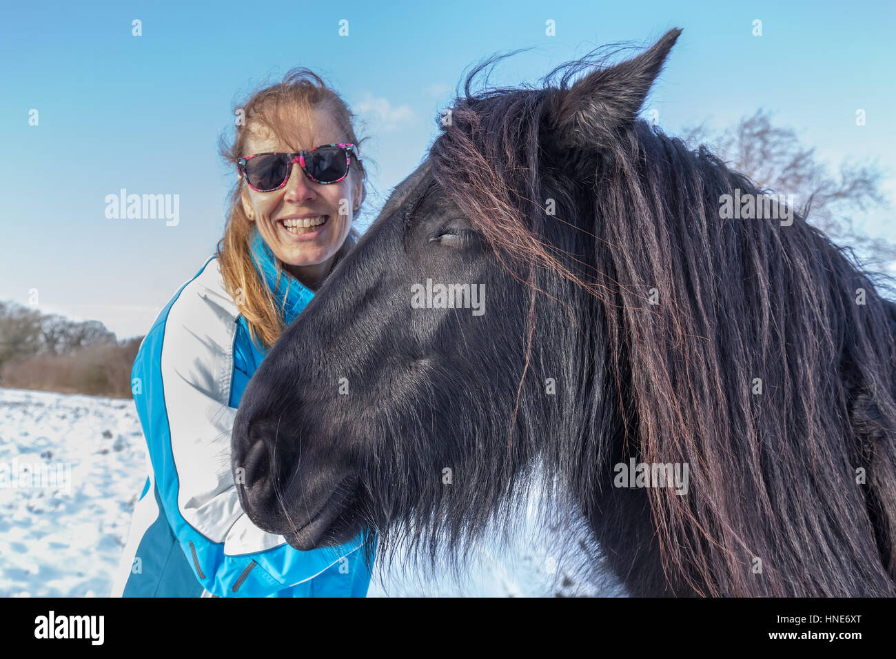 Retrato mujer caucásica con caballo frisón en invierno, la nieve Foto de stock