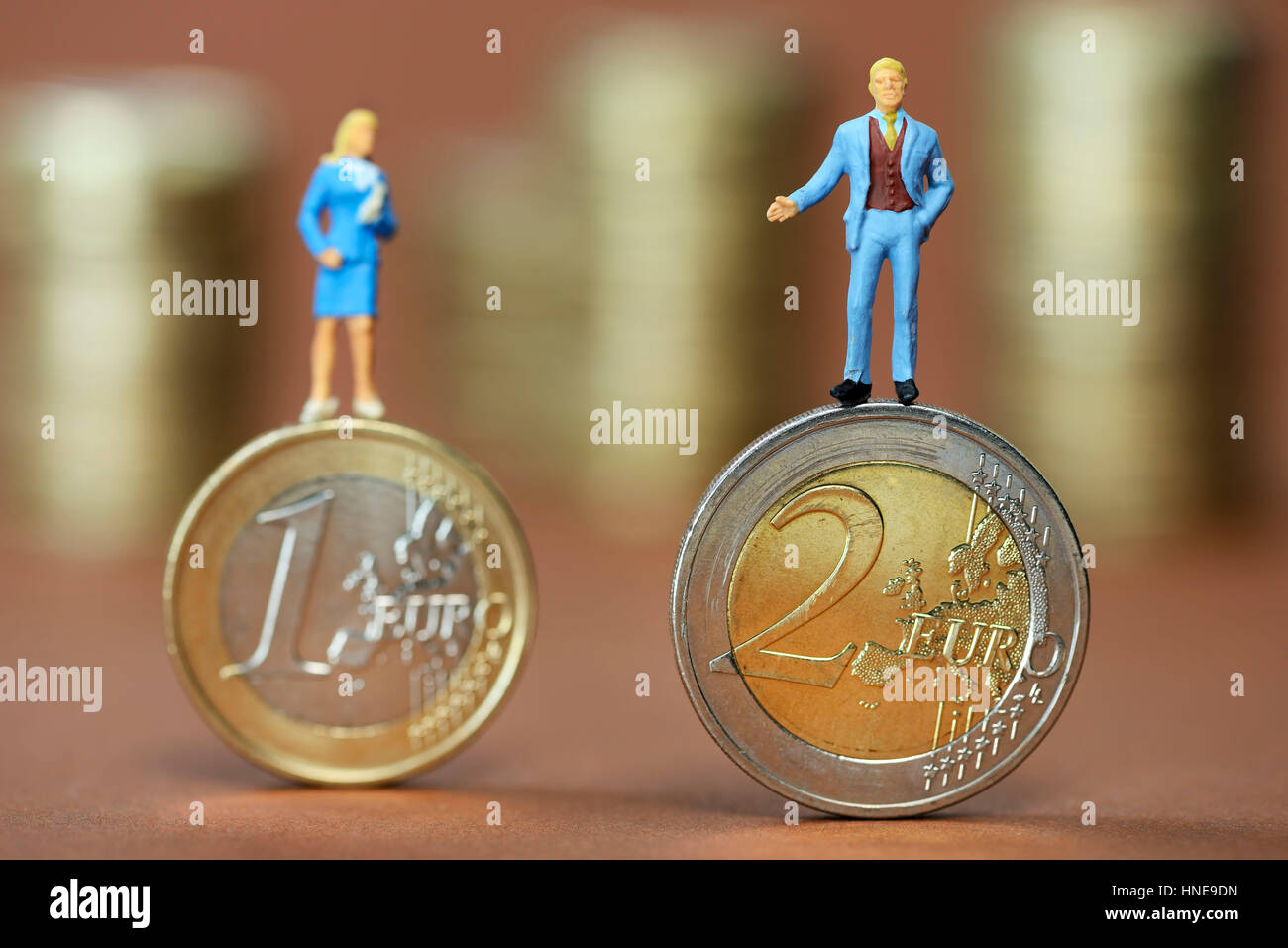 Figuras en miniatura de hombre y mujer en un uno y dos monedas de euro, fotografía simbólica de la desigualdad salarial, Miniaturfiguren von Mann und Frau auf Ein- und Zwe Foto de stock