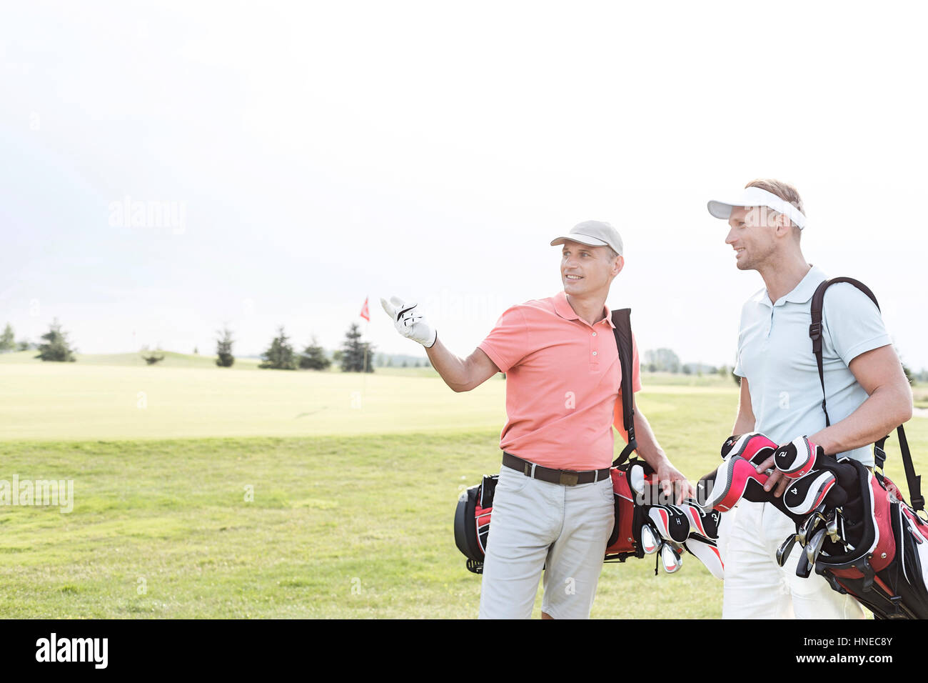 Hombre mostrando algo a un amigo en el campo de golf contra el cielo claro Foto de stock