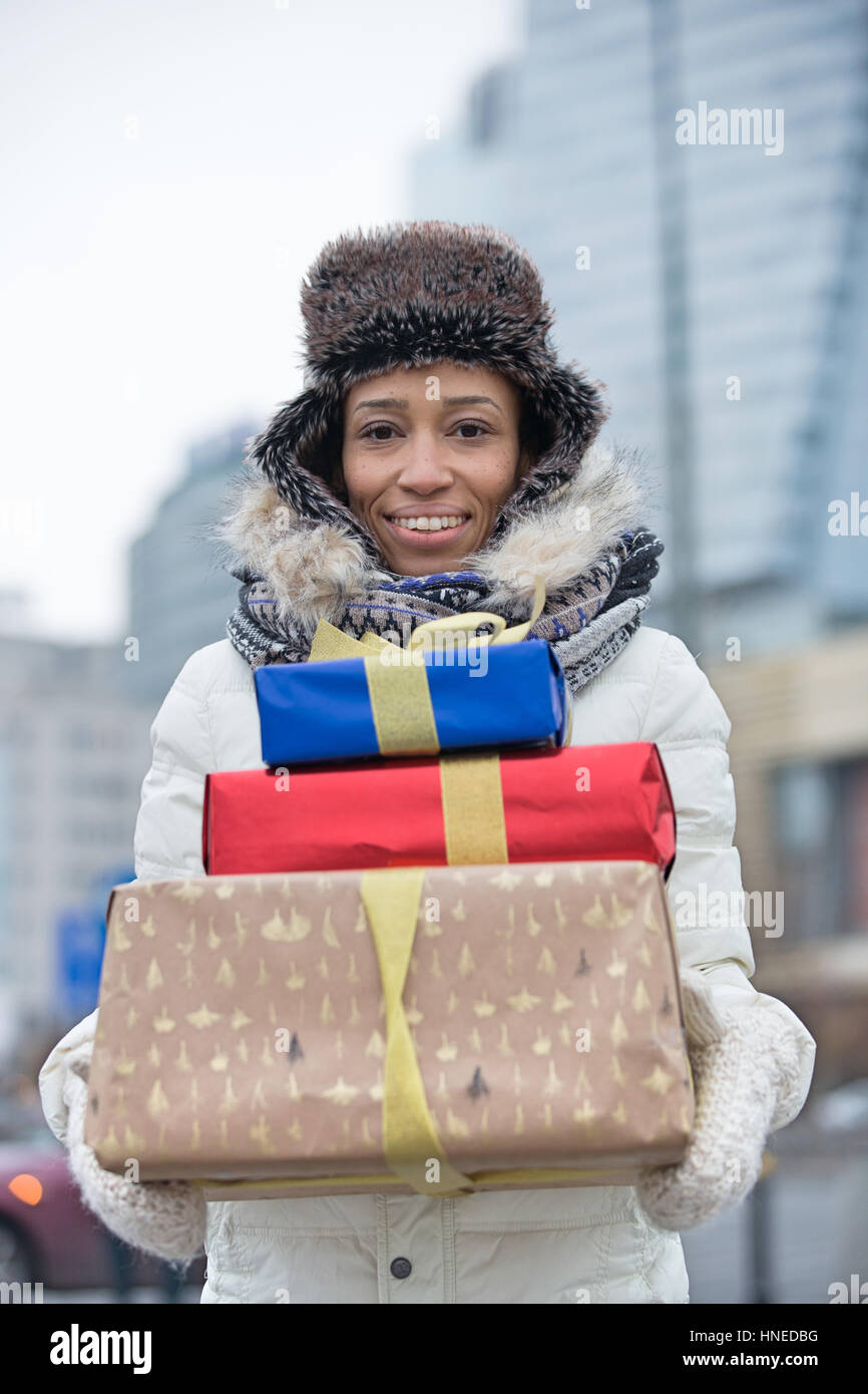 Retrato de mujer alegre y llevar regalos apilados durante el invierno Foto de stock
