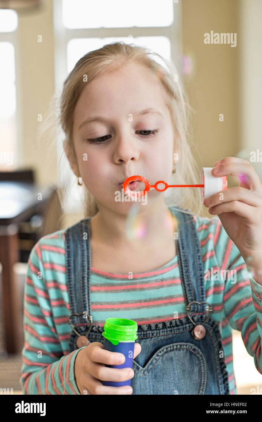 Linda niña jugando con bubble wand en casa Foto de stock