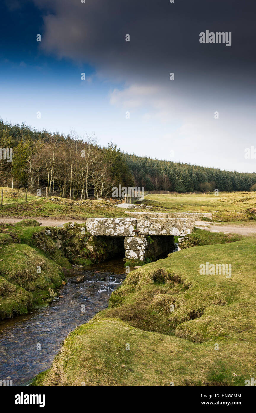 Un pequeño puente de granito sobre un pequeño río en terrenos Tor, designada como una Zona de Excepcional Belleza Natural en Bodmin Moor en Cornwall. Foto de stock