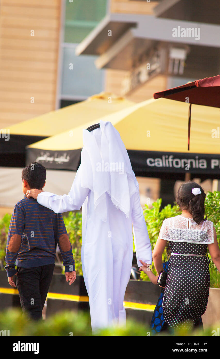 Dubai, Emiratos Árabes Unidos - 23 de octubre de 2016. Hombre en ropas tradicionales, pasear con los niños. Foto de stock
