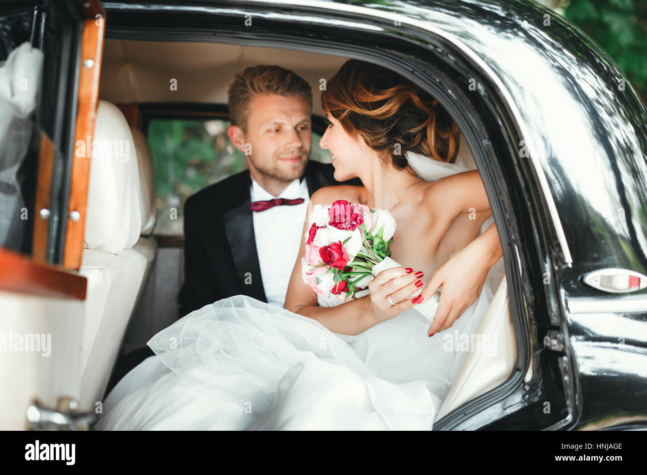 La novia y el novio sentado en el coche de boda Foto de stock