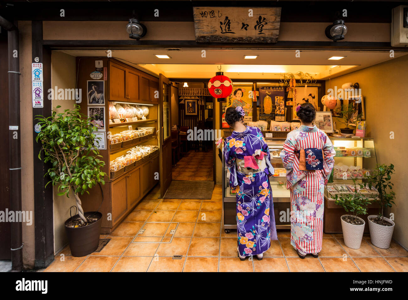 Dos jóvenes mujeres vistiendo trajes tradicionales japoneses, kimono en una panadería en el distrito Gion, Kioto, Japón Foto de stock