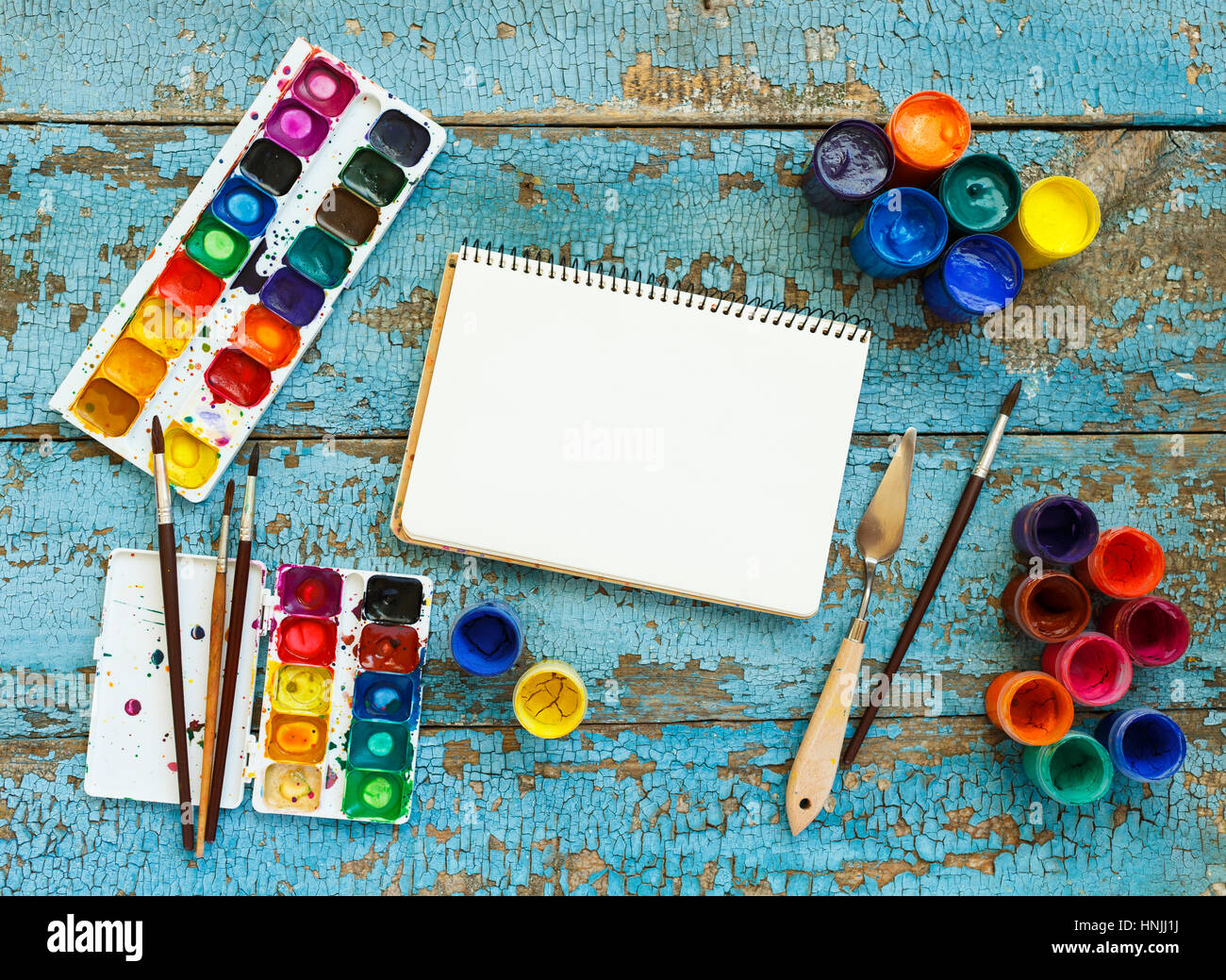 El arte de la pintura. Pintura: pinceles, pinturas, lápices de colores,  acuarela, libro blanco sobre un fondo de madera azul Fotografía de stock -  Alamy