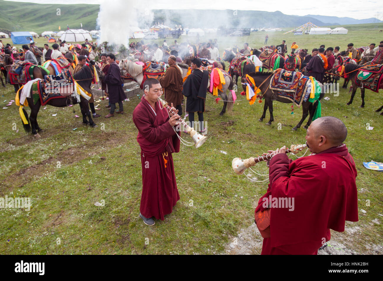 Monjes budistas tibetanos tocan los instrumentos tradicionales para bendecir a los jinetes antes de competición en el Festival de Caballos Manigango alta en la platea tibetano Foto de stock