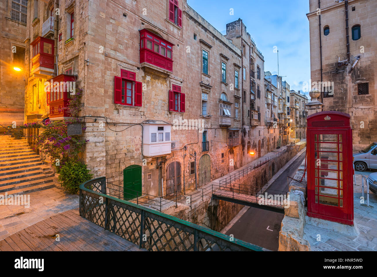 En Valletta, Malta - Rojo cuadro Teléfono de época británica y la pasarela roja tradicional y balcones en la antigua ciudad de La Valeta temprano en la mañana Foto de stock