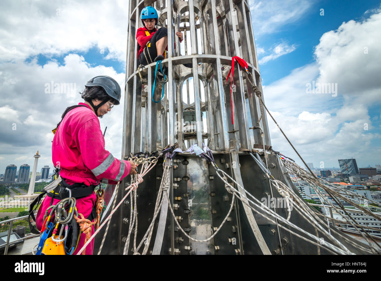 Yakarta, Indonesia. 17th de febrero de 2017. Los trabajadores voluntarios comprueban las anclas debajo de la cima de la torre de 66,66 metros de altura de la Mezquita Istiqlal en Yakarta, Indonesia. Docenas de miembros de los clubes de entusiastas de la actividad al aire libre, compañías de acceso a cuerdas y organizaciones de servicios de aventura al aire libre, se reúnen voluntariamente para limpiar la mezquita más grande del sudeste asiático para fortalecer la unidad nacional, la solidaridad y la tolerancia. Foto de stock