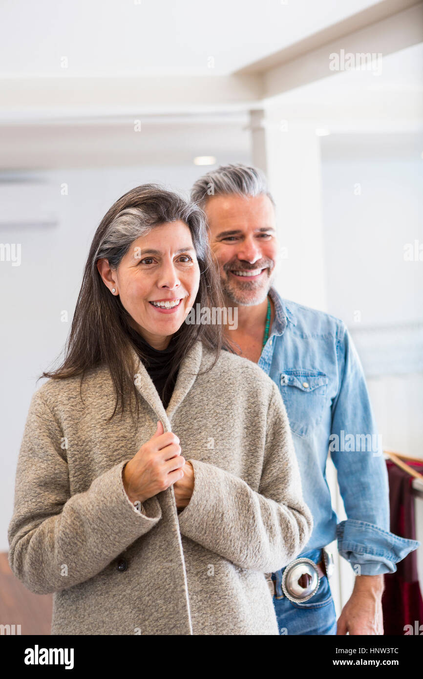 El hombre ve la mujer examinar abrigo en la tienda Foto de stock