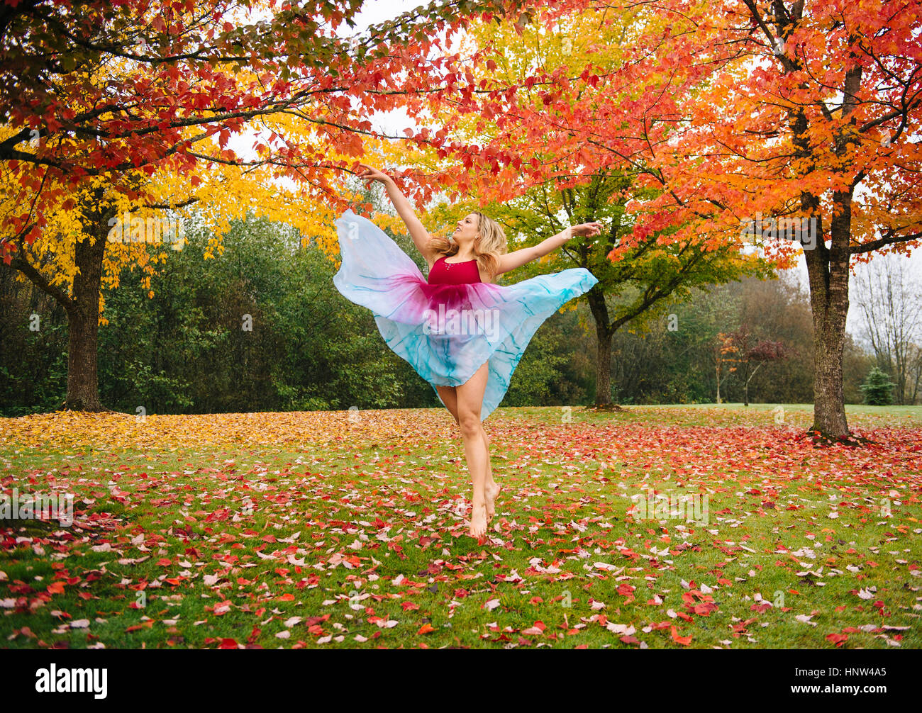 Bailarina caucásica bailando en las hojas de otoño en el parque Foto de stock