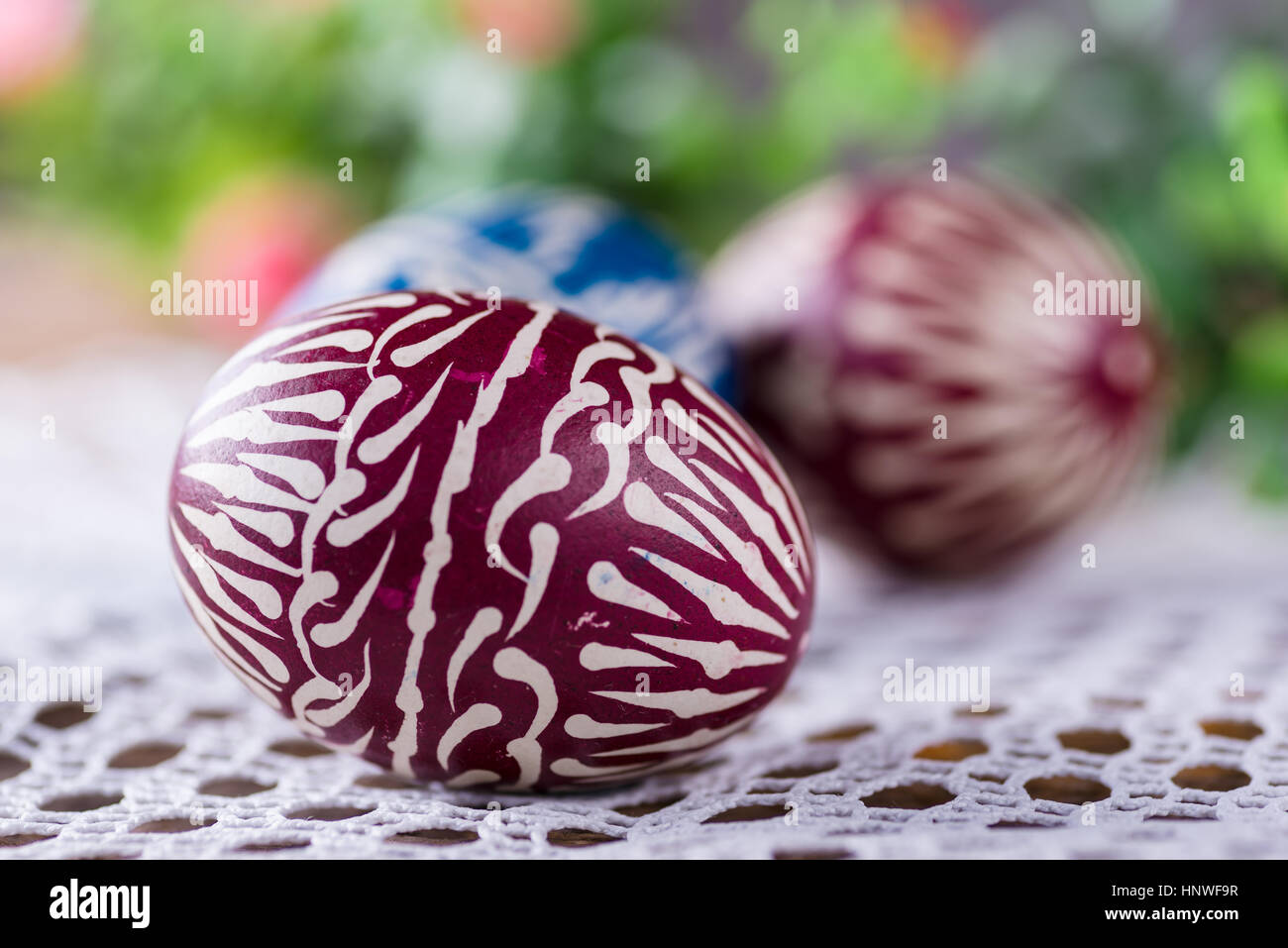 Los huevos de Pascua pintados a mano, colourised, sobre la mesa de madera y servilletas bordadas Foto de stock