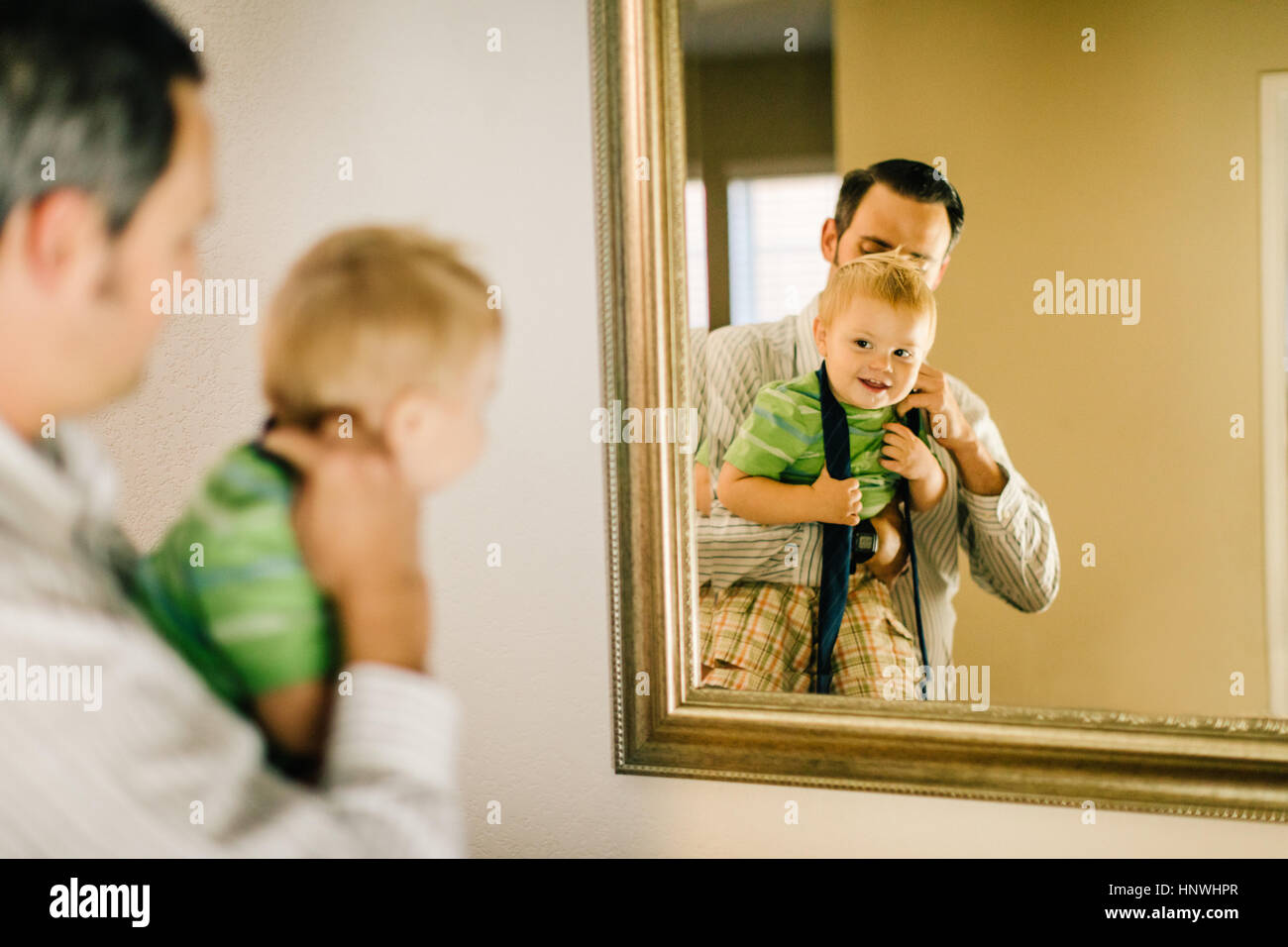 Padre poner neck tie el joven hijo, reflejado en el espejo Fotografía de  stock - Alamy