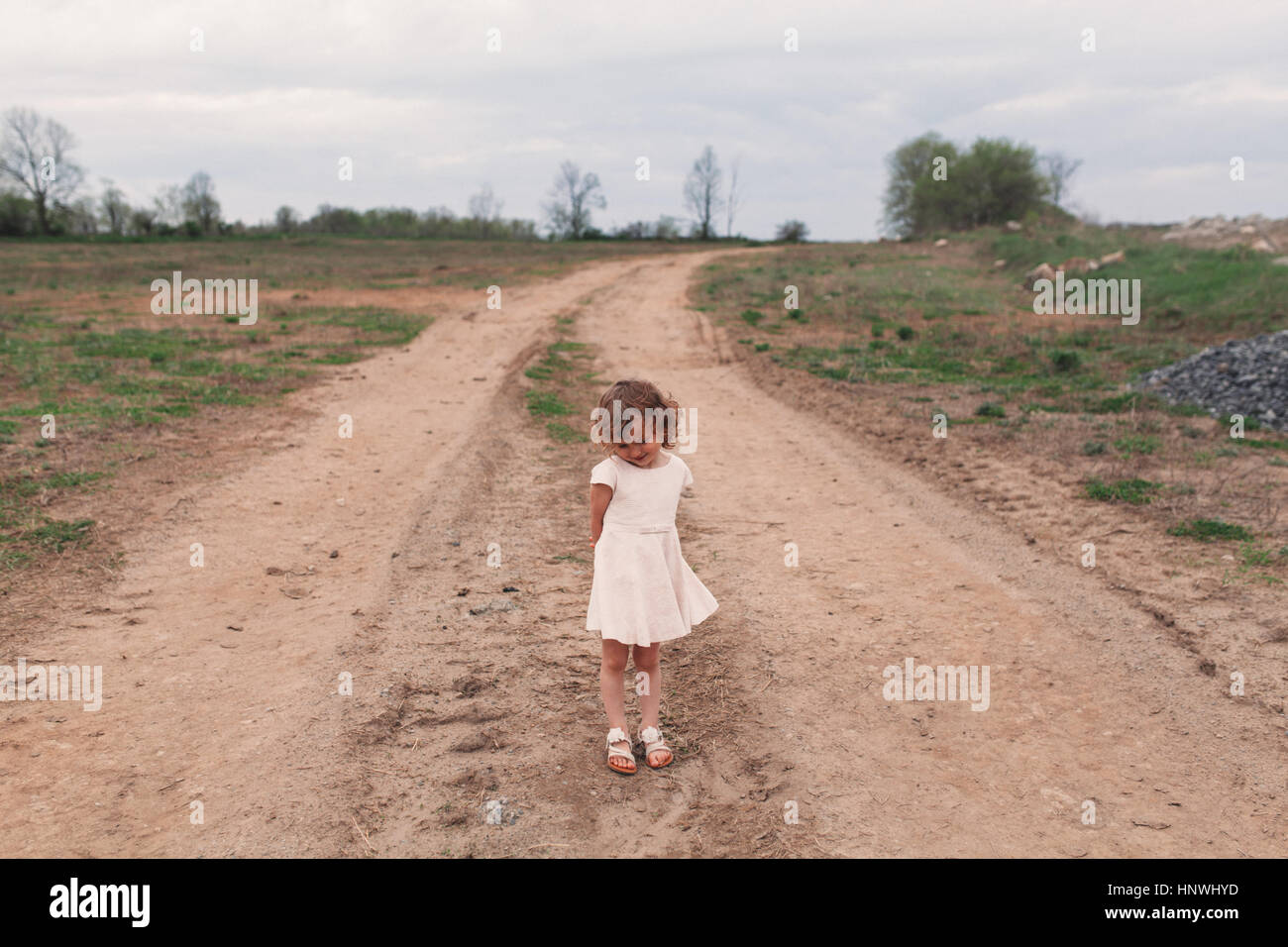 Retrato de la tímida niña de pie en la pista de tierra rural Foto de stock