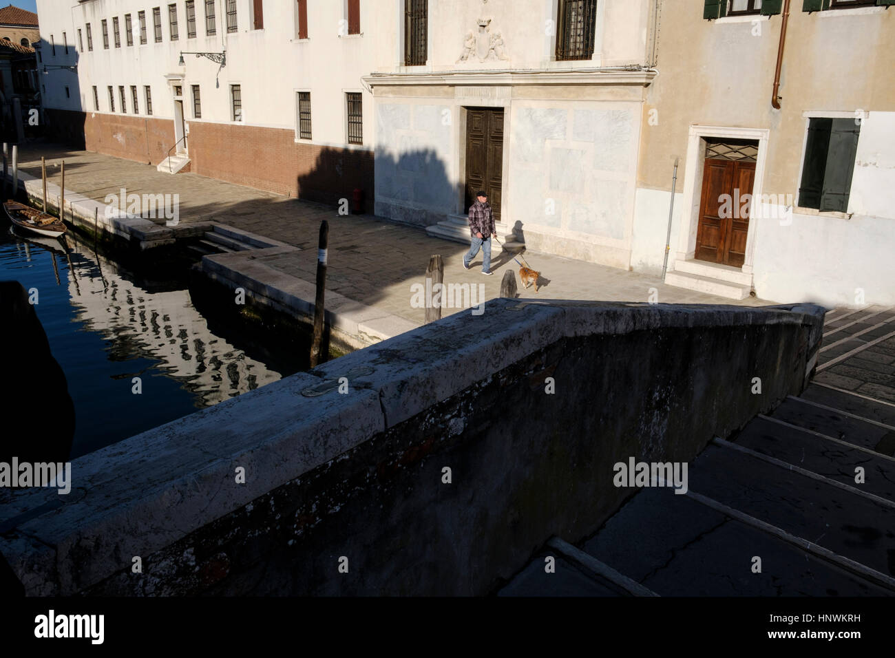 Hombre caminando a su perro a lo largo de un canal. Venecia, Italia Foto de stock