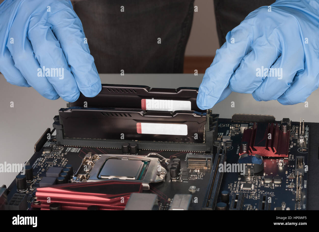 Cerca del hombre manos con guantes de instalar el módulo de memoria RAM DDR4  en la ranura de la placa base Fotografía de stock - Alamy