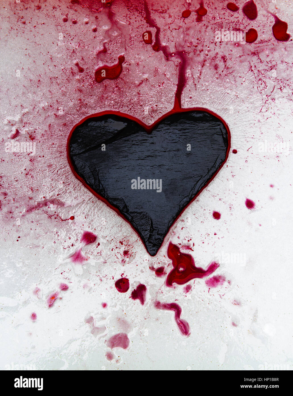 Pizarra y corazón de tinta roja sobre el hielo Foto de stock