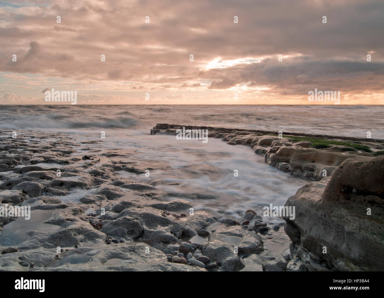 Las olas ruedan como la marea sube al amanecer en la costa noreste de la UK Foto de stock