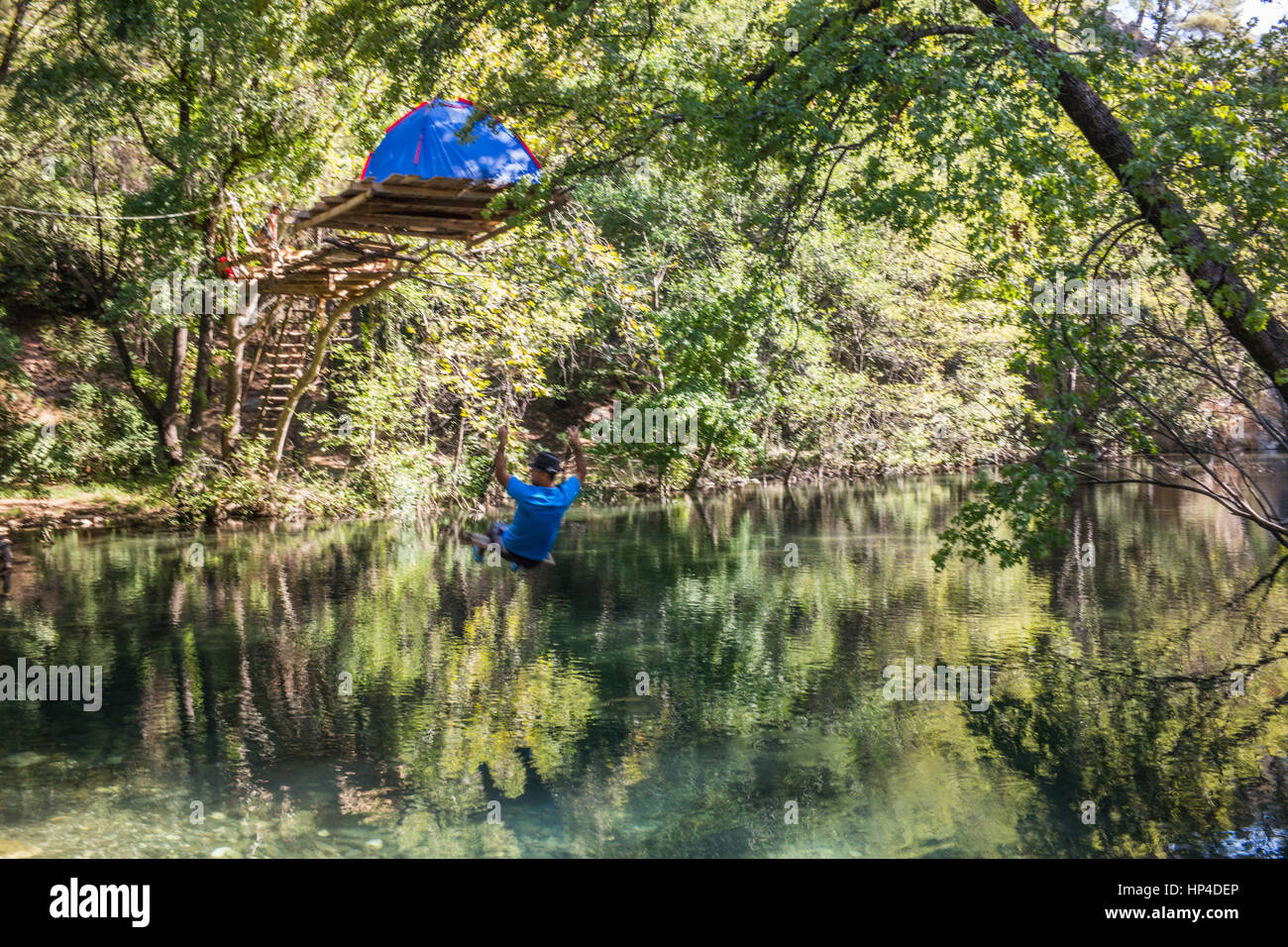 Hombre balanceándose sobre el río - Campamento carpa por encima del río Foto de stock