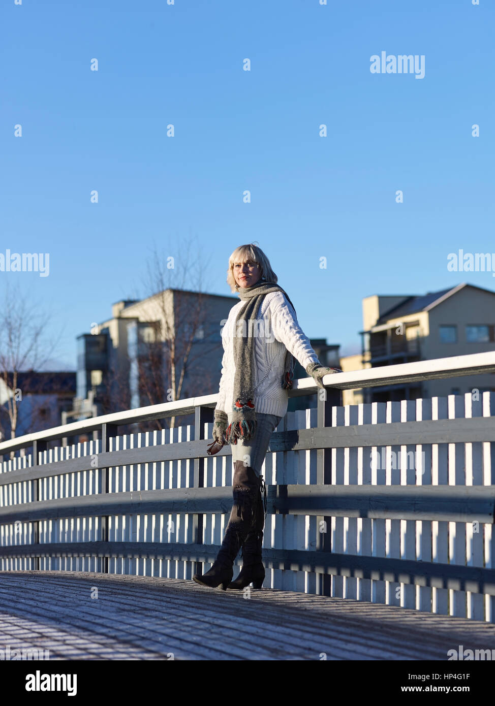 Mujer madura, apoyado en la barandilla del puente, soleado día de invierno Foto de stock