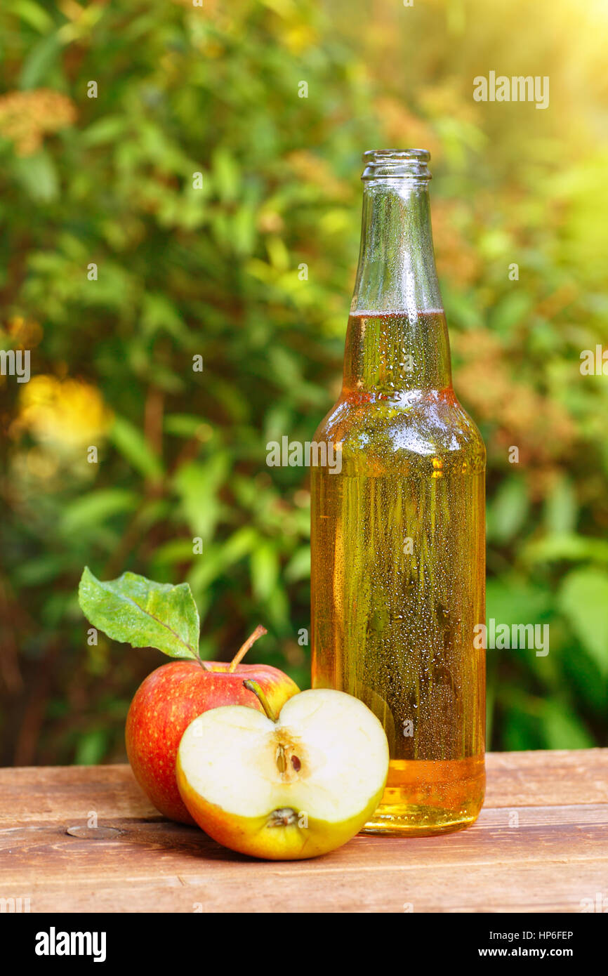 La sidra en botella de cristal y maduras manzanas frescas en la mesa de madera en el fondo de la naturaleza. Bebidas sidra de manzana sobre la mesa de madera. Bodegón con Apple ci Foto de stock