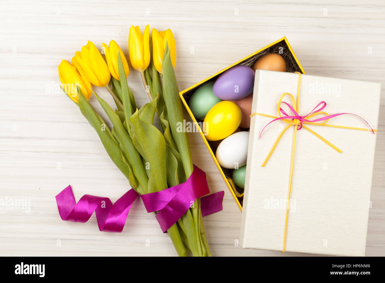 Los huevos de Pascua en un recuadro amarillo con coloridos tulipanes y Pink Ribbon Foto de stock