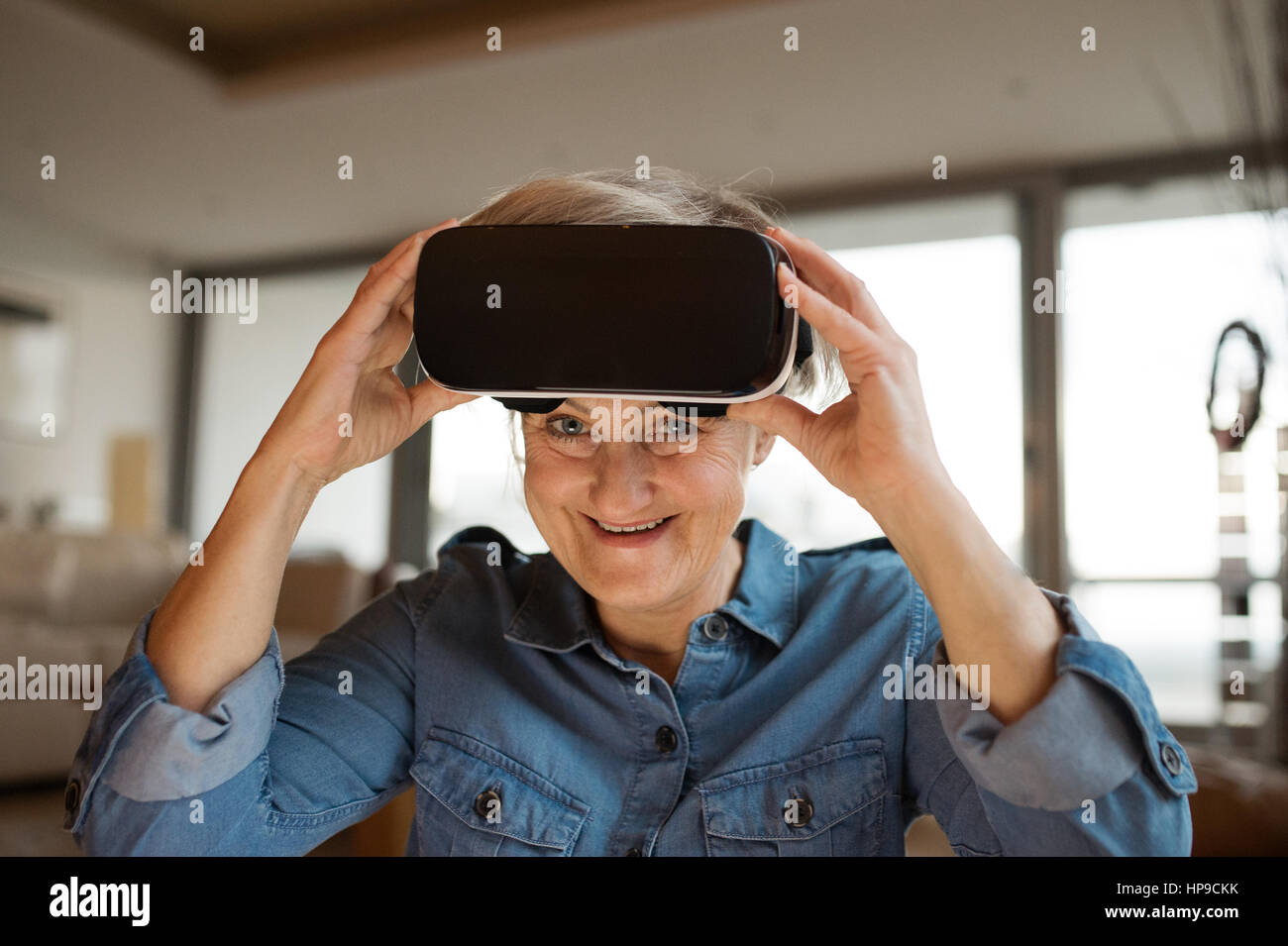 Senior mujer vistiendo gafas de realidad virtual en casa Foto de stock