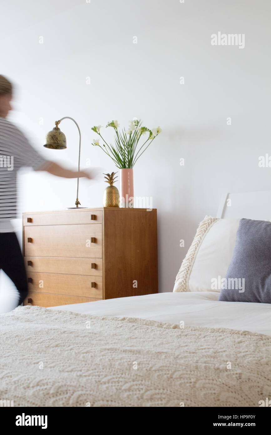 Una mujer se mueve a través de un dormitorio con muebles modernos midcentury Foto de stock