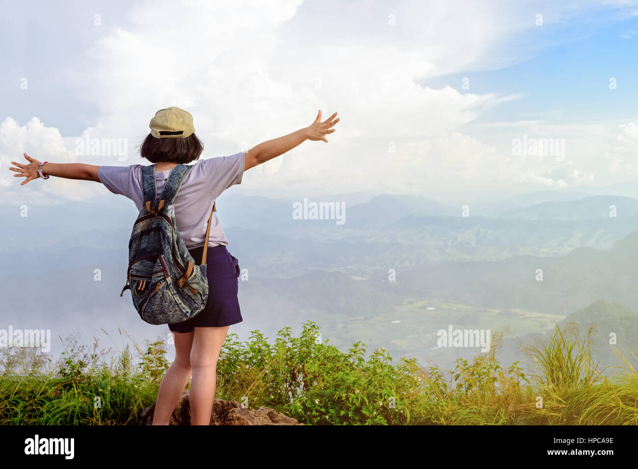 Los adolescentes niña feliz excursionista con mochila y tapar los brazos abiertos mirando la hermosa naturaleza paisaje de alta montaña en el mirador del Parque Forestal de Phu Chi Fa Foto de stock