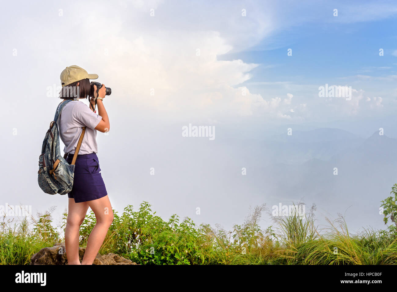 Excursionistas adolescentes asiáticas chica con cámara digital y mochila tomando foto bellos parajes naturales de sierra sky cloud y niebla durante la puesta de sol en invierno en la montaña Foto de stock