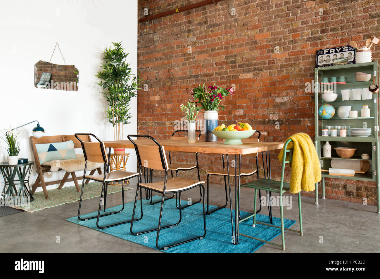 Mesa de comedor y sillas en un gran espacio urbano con paredes de ladrillos expuestos Foto de stock