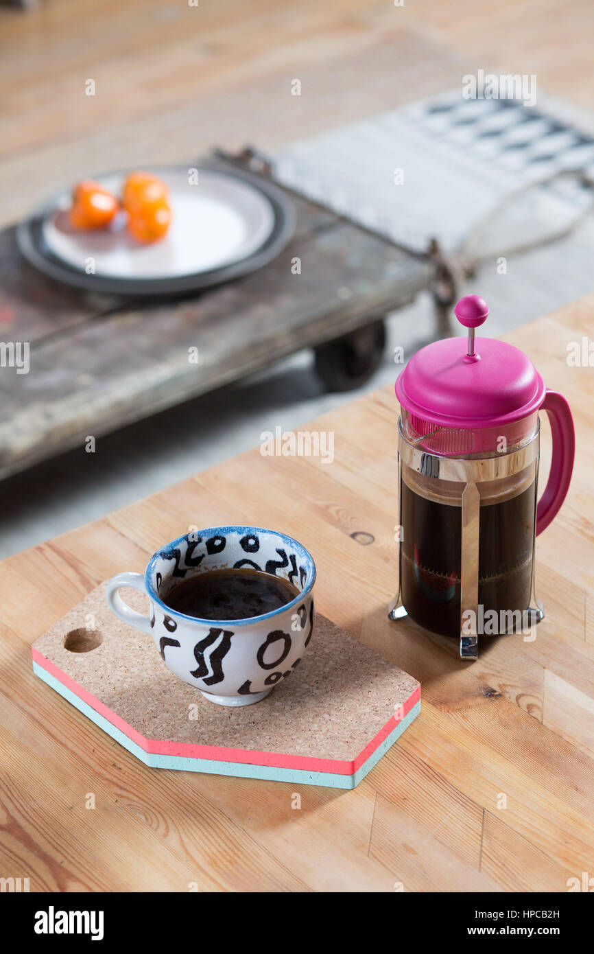 Una rosa de cafetera y una taza de café negro sentarse en una mesa de madera Foto de stock