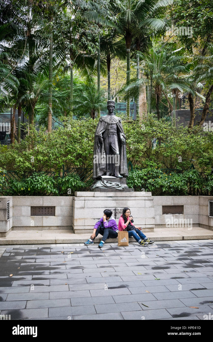 Turistas descansando delante de la estatua de bronce del rey George VI en Hong Kong zoo (Zoológico y Jardín Botánico) Foto de stock