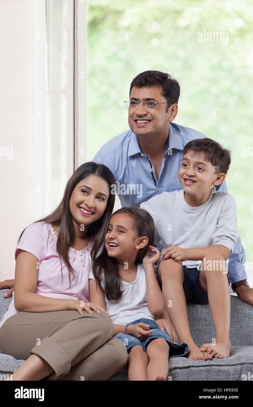 Retrato de familia con dos hijos, sentado en el sofá juntos Foto de stock