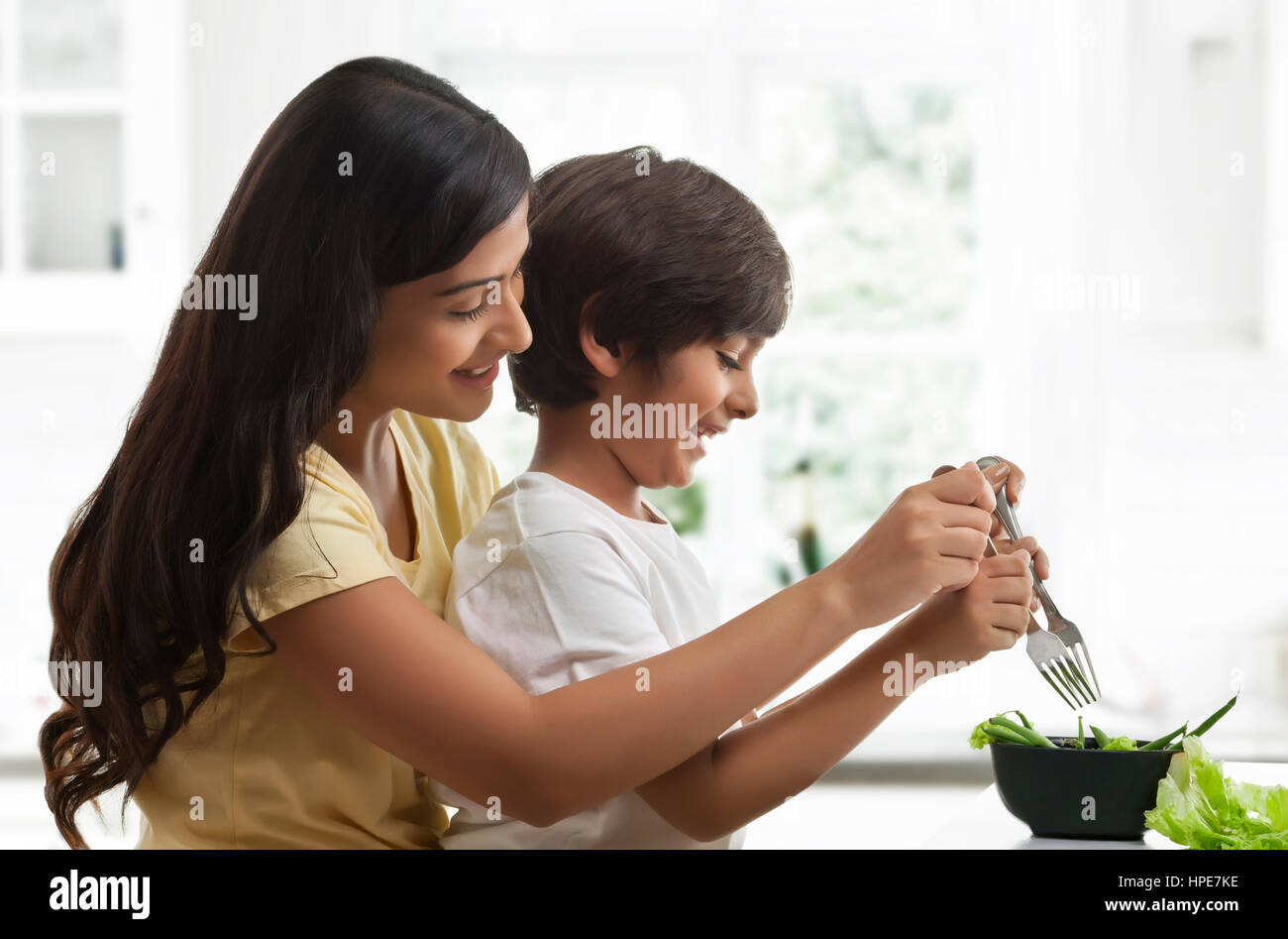 Sonriente madre e hijo hacer ensalada para el almuerzo en la cocina Foto de stock