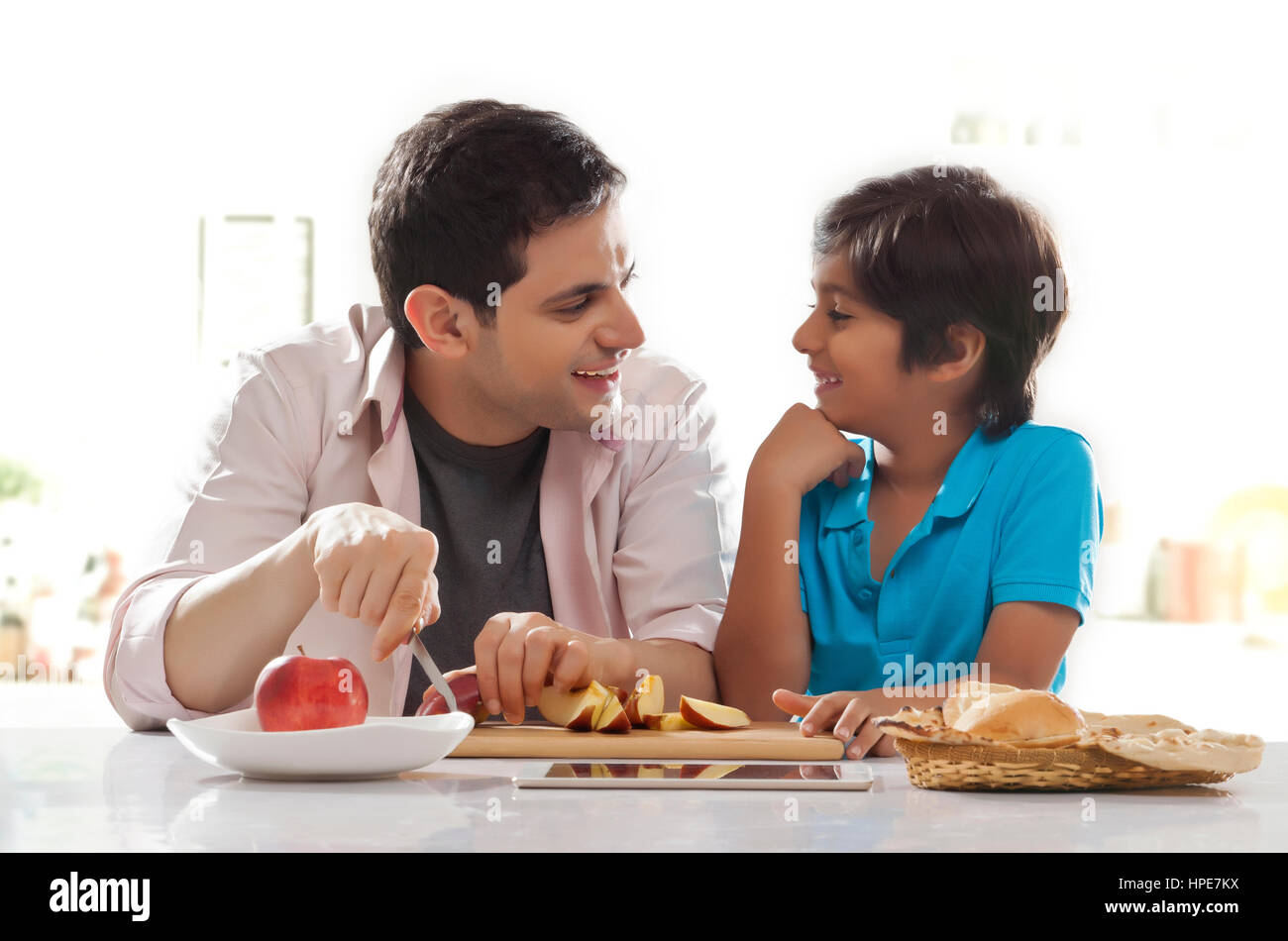 Padre e hijo feliz mirarse sentado en una mesa para el desayuno Foto de stock
