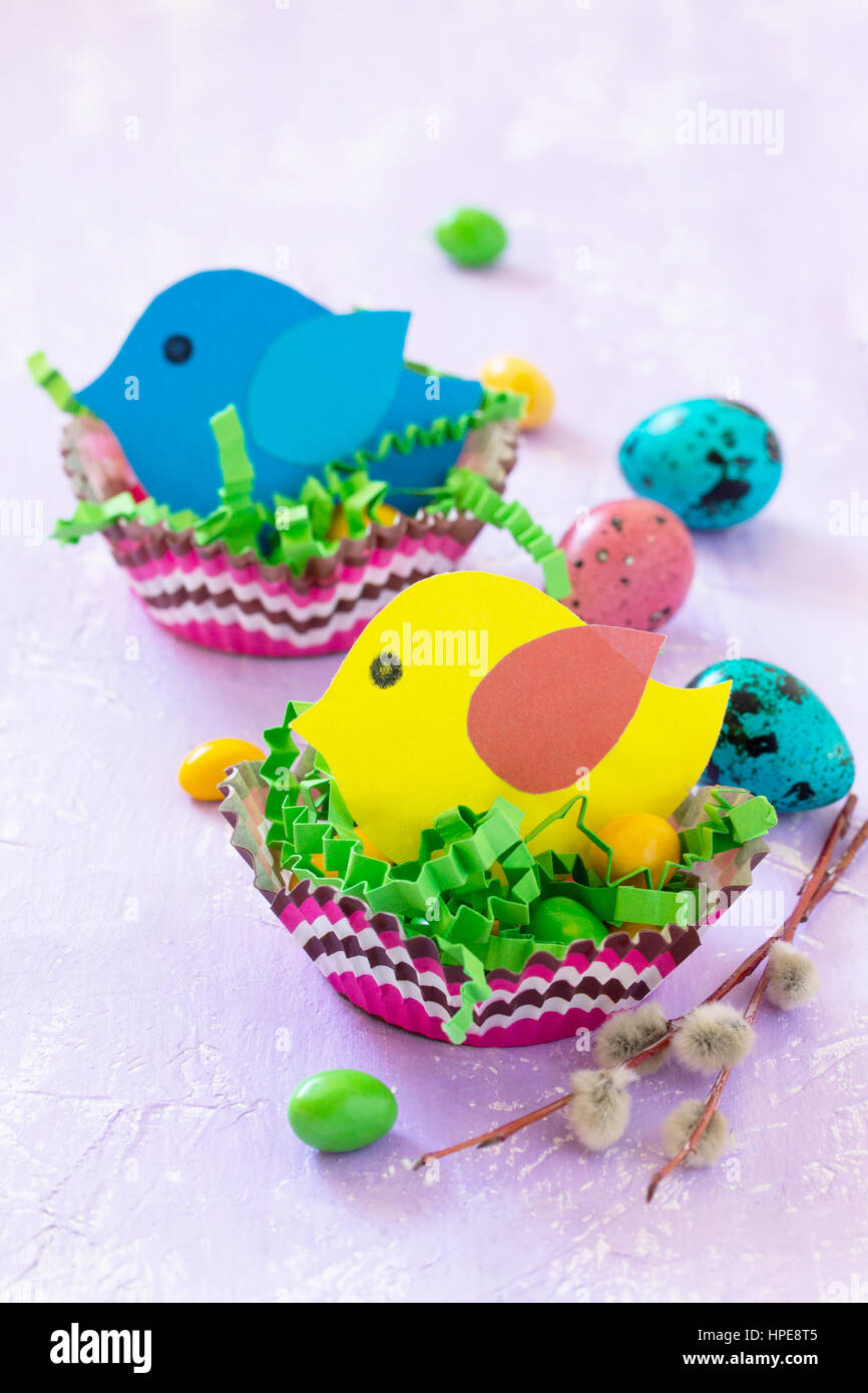 Adornos de Pascua mesa para niños. Decoración de la mesa de Pascua nido de  pájaro con un bebé y los caramelos, papel pintado de huevos de codorniz.  Copie el espacio Fotografía de