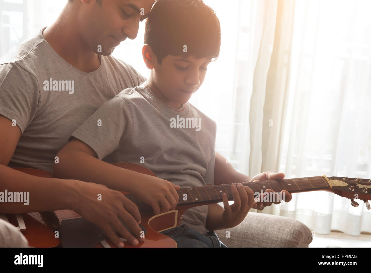 Padre enseñar a su hijo a tocar la guitarra Foto de stock