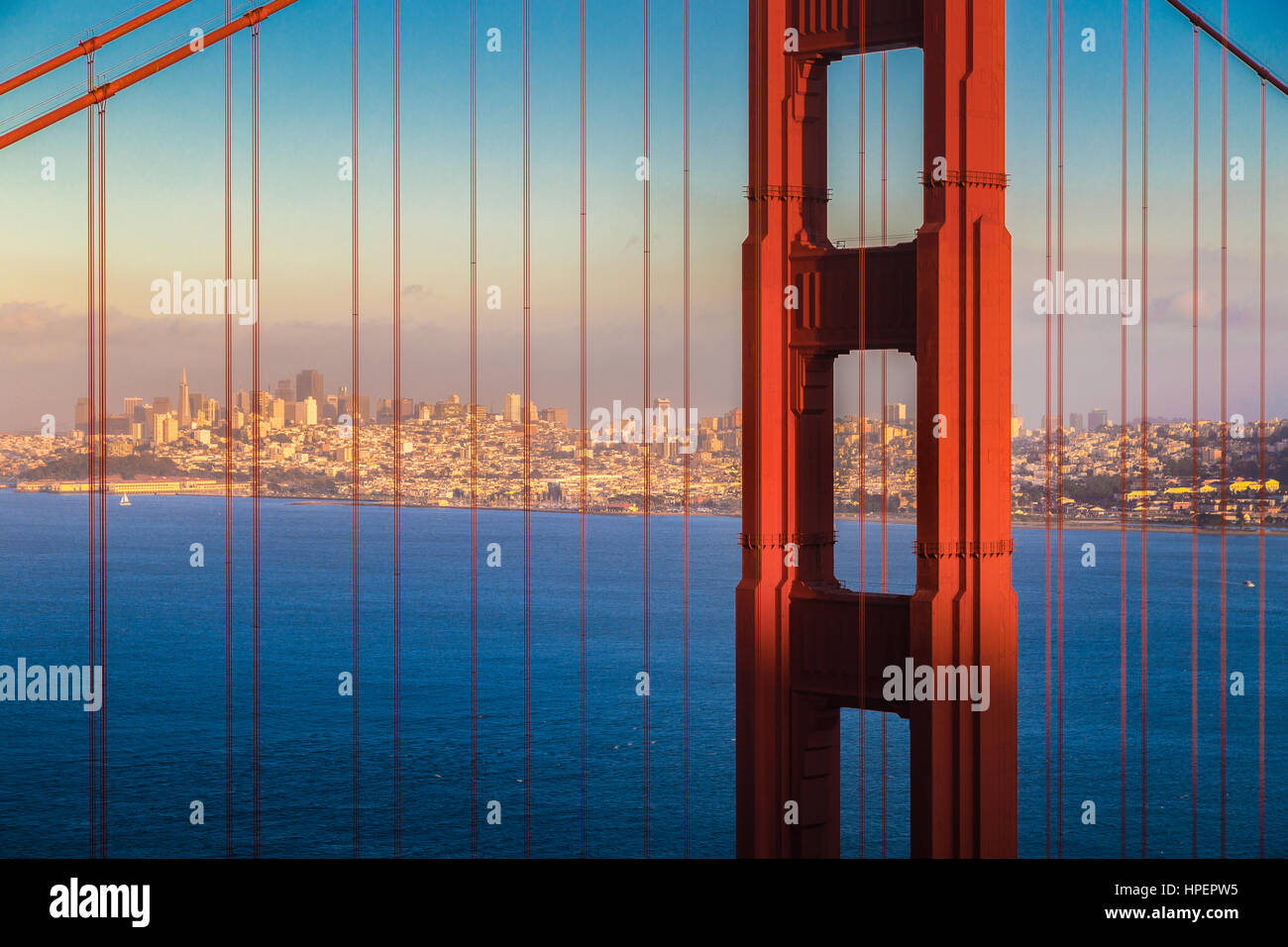 Vista clásica del famoso puente Golden Gate con el horizonte de la ciudad de San Francisco en el fondo iluminado en la hermosa luz del atardecer dorado al atardecer Foto de stock