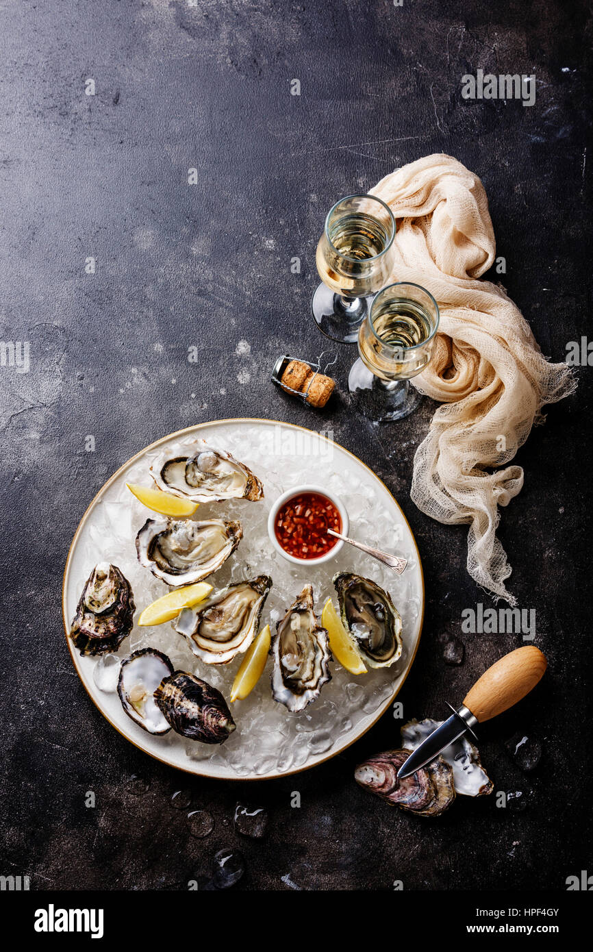 Abra las ostras con salsa picante y champagne en textura de piedra oscura espacio copia de fondo Foto de stock